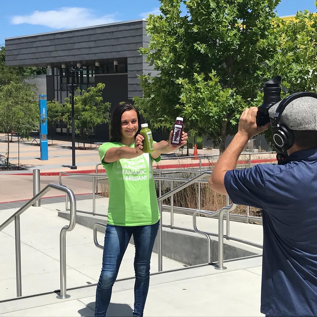 Elizabeth of JuiceAlize on a photo shoot holding two cold-pressed juices